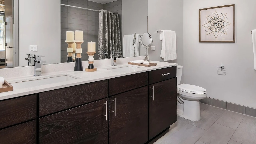 Spacious master bathroom with a double vanity, large mirror, elegant lighting, and a walk-in shower at Lofts at River East in Chicago