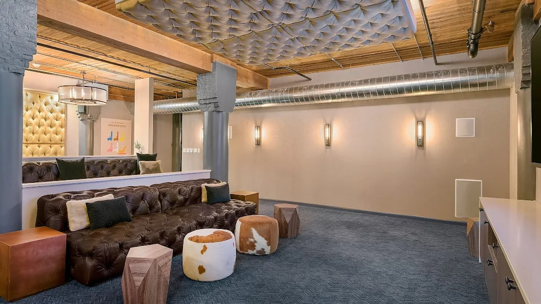 Plush media room with comfortable tiered seating, a large screen, and unique tufted ceiling details, perfect for movie nights at Lofts at River East in Chicago