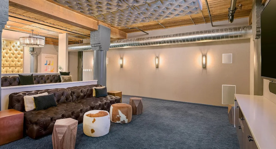 Plush media room with comfortable tiered seating, a large screen, and unique tufted ceiling details, perfect for movie nights at Lofts at River East in Chicago