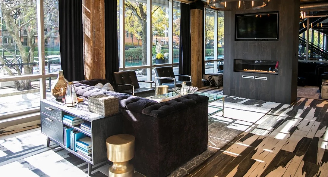 Inviting resident lounge with comfortable seating, a modern fireplace, and large windows overlooking green space at Lofts at River East in Chicago