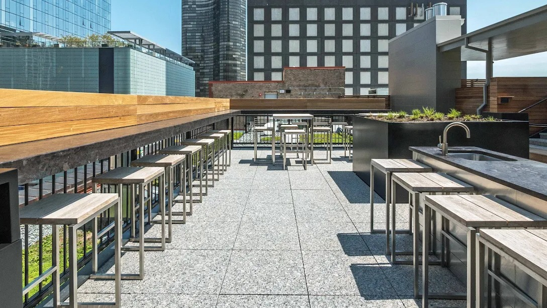 Stylish rooftop bar and grilling area with bar stools, sleek countertops, and panoramic city views at Lofts at River East in Chicago