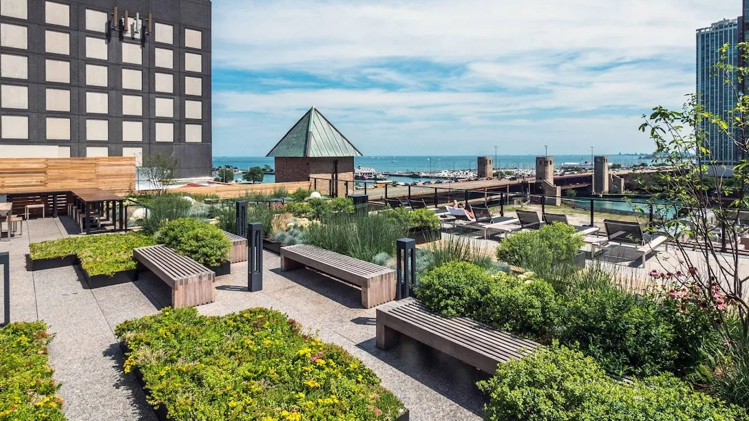 Expansive rooftop lounge area with outdoor seating, green spaces, and panoramic views of the Chicago River and city skyline at Lofts at River East in Chicago