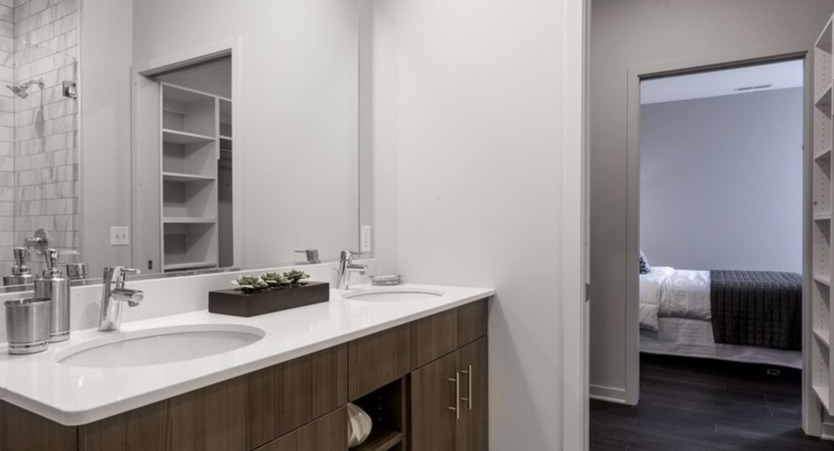 A modern bathroom at Luxe on Chicago Apartments with a double vanity, leading to a spacious walk-in closet