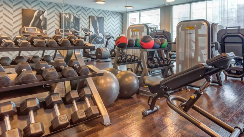 A well-equipped fitness center at Luxe on Chicago Apartments with various free weights, machines, and cardio equipment