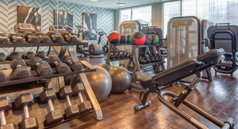 A well-equipped fitness center at Luxe on Chicago Apartments with various free weights, machines, and cardio equipment
