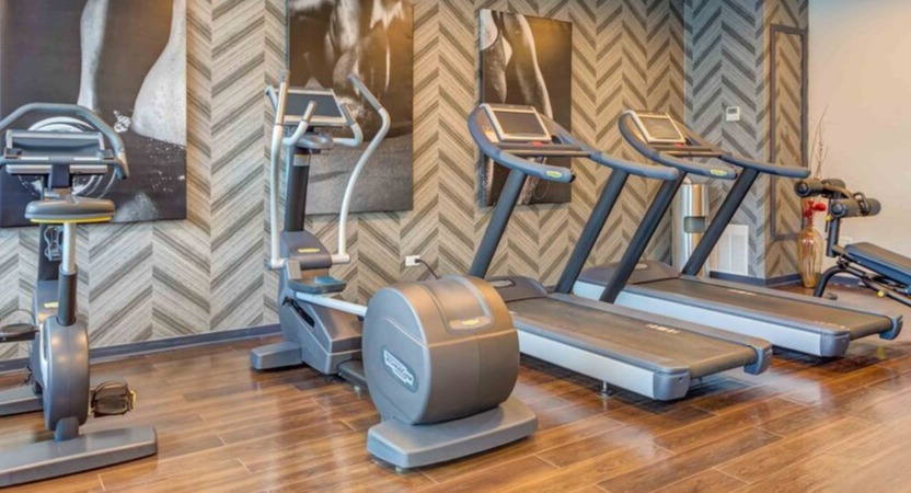 A modern gym area at Luxe on Chicago Apartments featuring treadmills, ellipticals, and exercise bikes for residents
