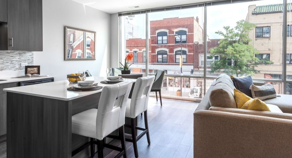 A modern kitchen and living area at Luxe on Chicago Apartments, with floor-to-ceiling windows overlooking city buildings