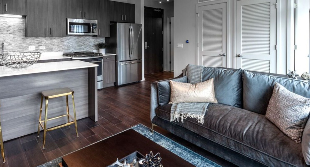 A spacious living area at Luxe on Chicago Apartments with a comfortable couch, leading into a bedroom entryway