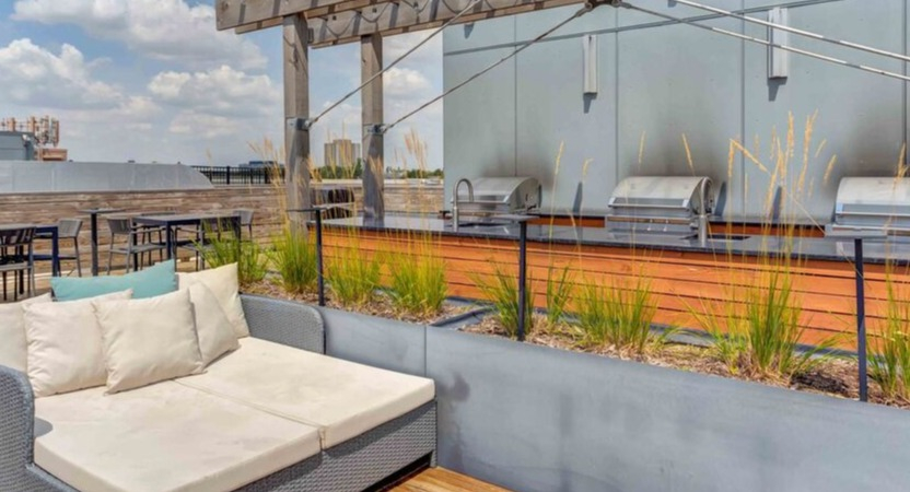 An outdoor rooftop area at Luxe on Chicago Apartments with BBQ grills and comfortable lounge seating under a pergola