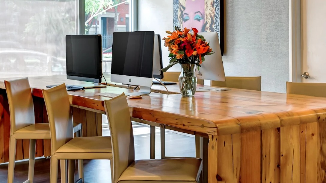 Contemporary business center with iMac computers, wood table, and bright decor at Luxe on Madison Apartments in Chicago