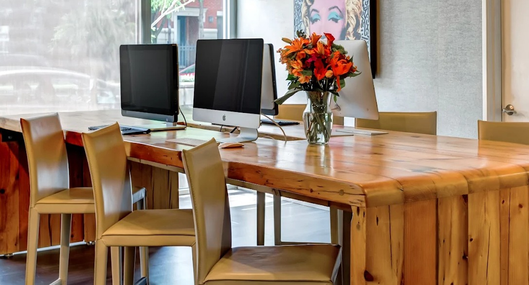 Contemporary business center with iMac computers, wood table, and bright decor at Luxe on Madison Apartments in Chicago