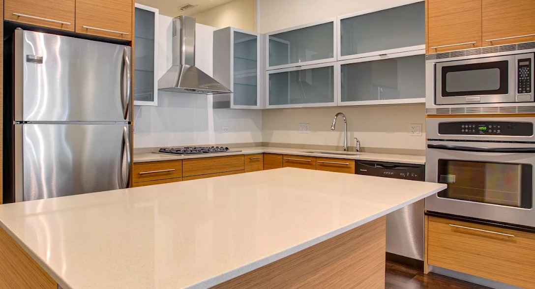 Sleek modern kitchen with stainless steel appliances, wood cabinets, and island at Luxe on Madison Apartments in Chicago