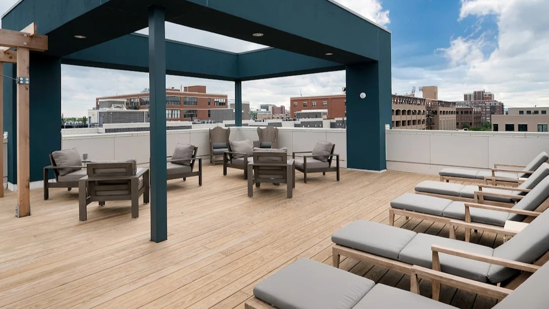 Modern rooftop lounge with wood decking, shaded seating, and city views at Luxe on Madison Apartments in Chicago