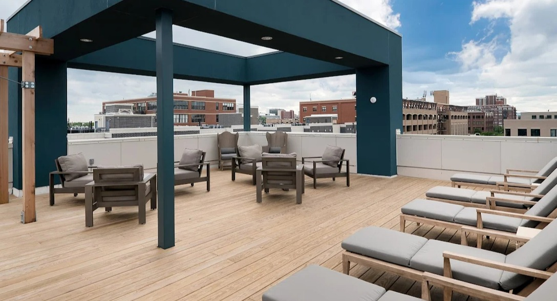 Modern rooftop lounge with wood decking, shaded seating, and city views at Luxe on Madison Apartments in Chicago