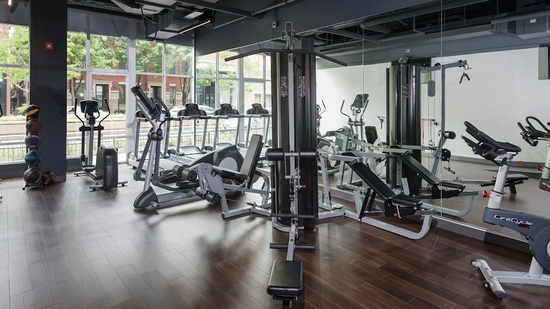 State-of-the-art fitness center with cardio machines, weight equipment, and large windows at Luxe on Madison Apartments in Chicago