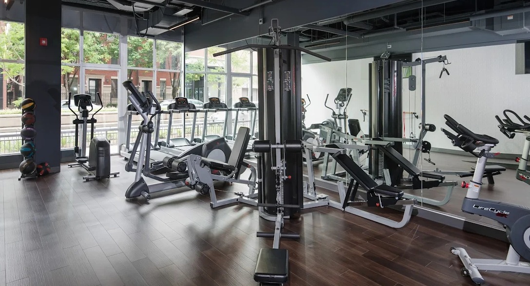 State-of-the-art fitness center with cardio machines, weight equipment, and large windows at Luxe on Madison Apartments in Chicago
