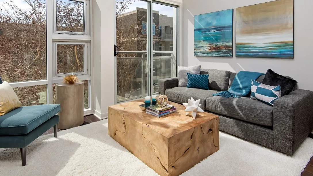 Bright living room with a comfortable sofa, stylish coffee table, and access to a private balcony at Luxe on Madison Apartments in Chicago