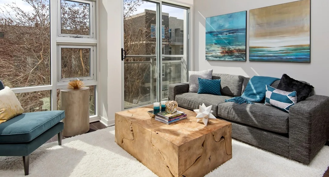 Bright living room with a comfortable sofa, stylish coffee table, and access to a private balcony at Luxe on Madison Apartments in Chicago