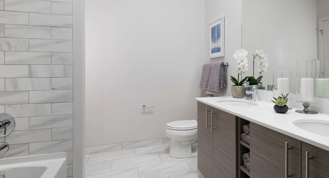 Spacious modern bathroom with a double vanity, large mirror, and a sleek shower-tub combination at Luxe on Madison Apartments in Chicago
