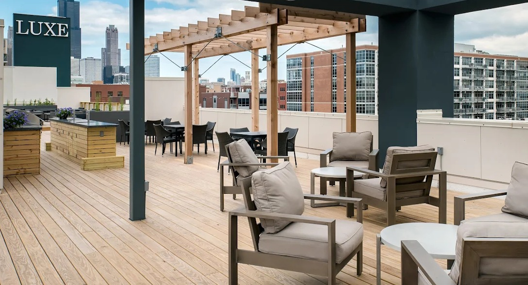 Spacious rooftop deck with comfortable lounge seating, dining areas, and city views at Luxe on Madison Apartments in Chicago