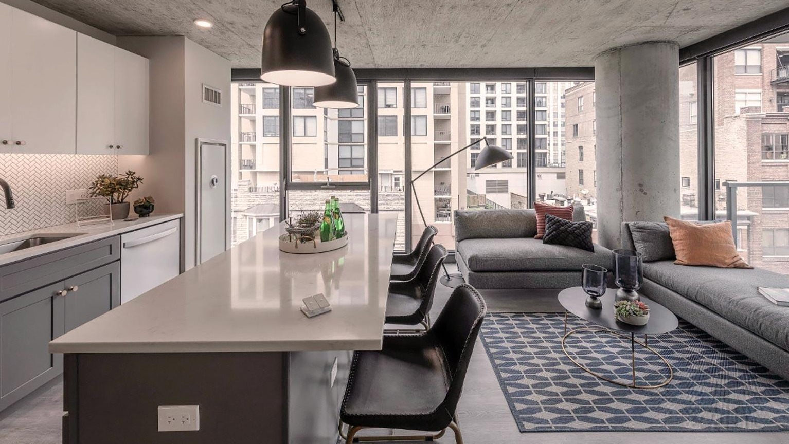 Open-concept kitchen and living area with a breakfast bar, comfortable sectional sofa, and a private balcony with city views at Marlowe Apartments in Chicago