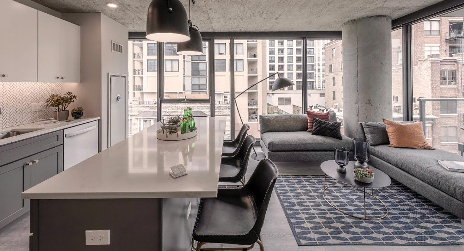 Open-concept kitchen and living area with a breakfast bar, comfortable sectional sofa, and a private balcony with city views at Marlowe Apartments in Chicago