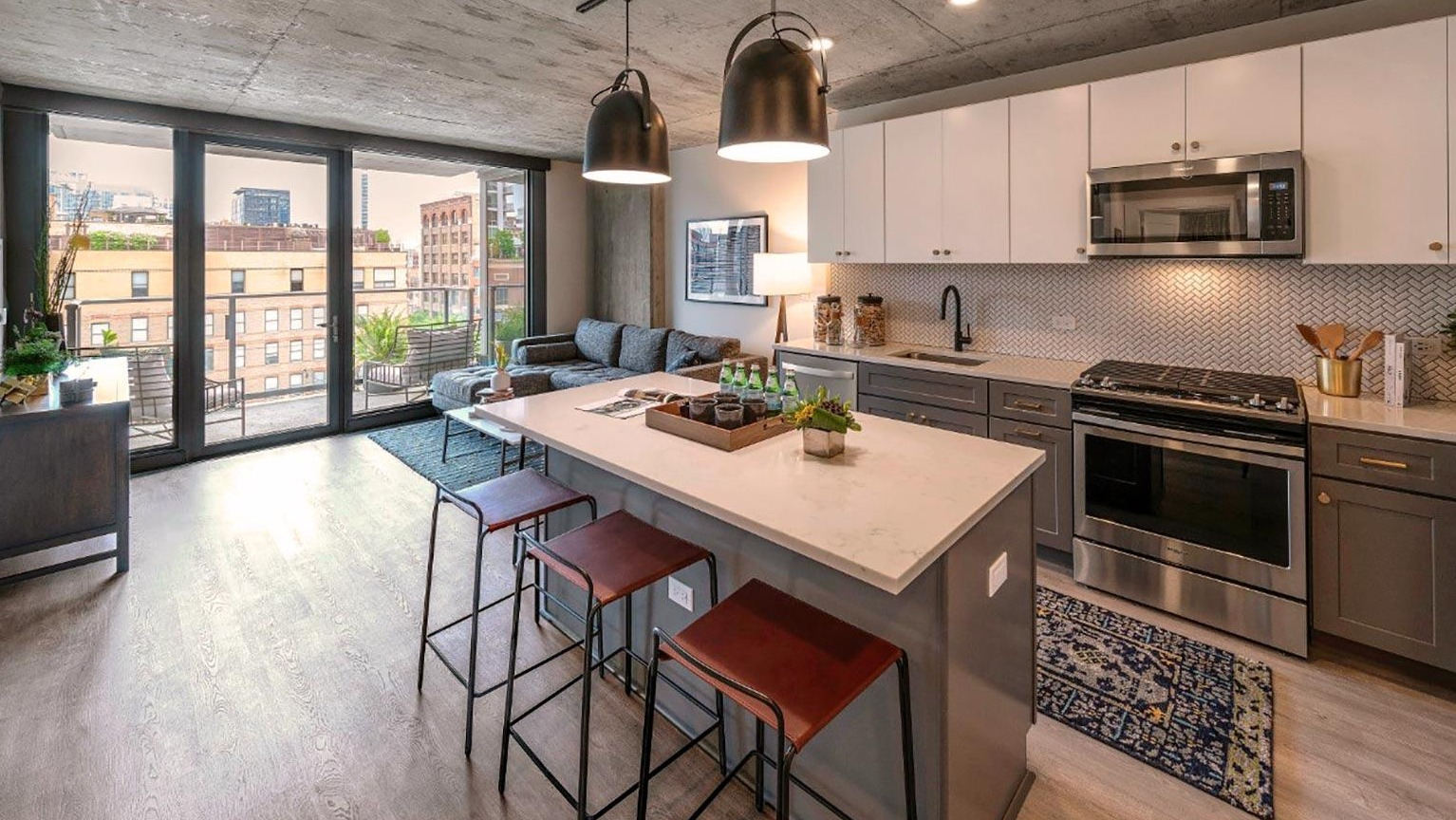 Open-concept kitchen and living area with a large island, modern appliances, and a balcony with urban views at Marlowe Apartments in Chicago