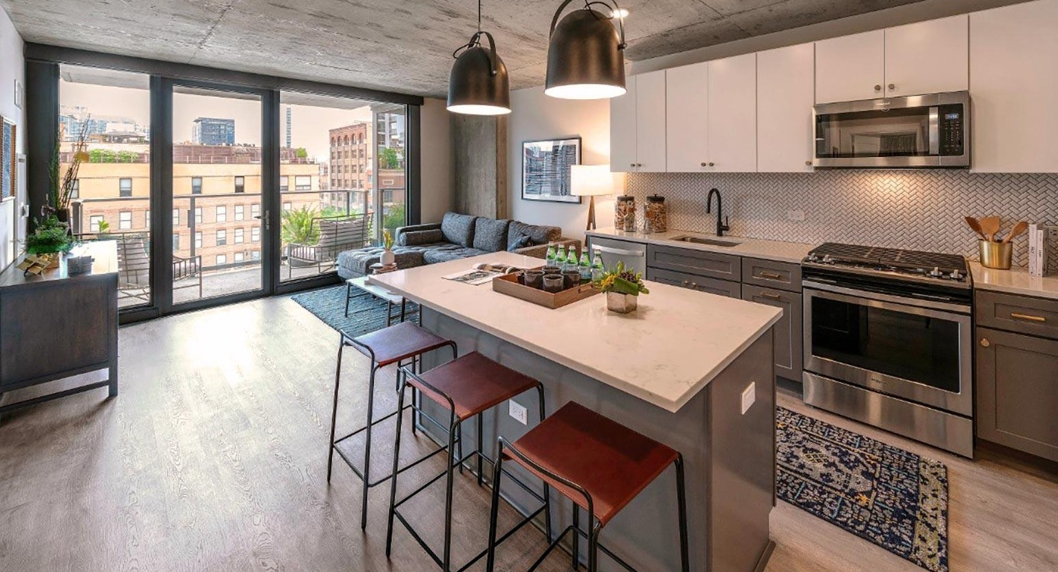 Open-concept kitchen and living area with a large island, modern appliances, and a balcony with urban views at Marlowe Apartments in Chicago