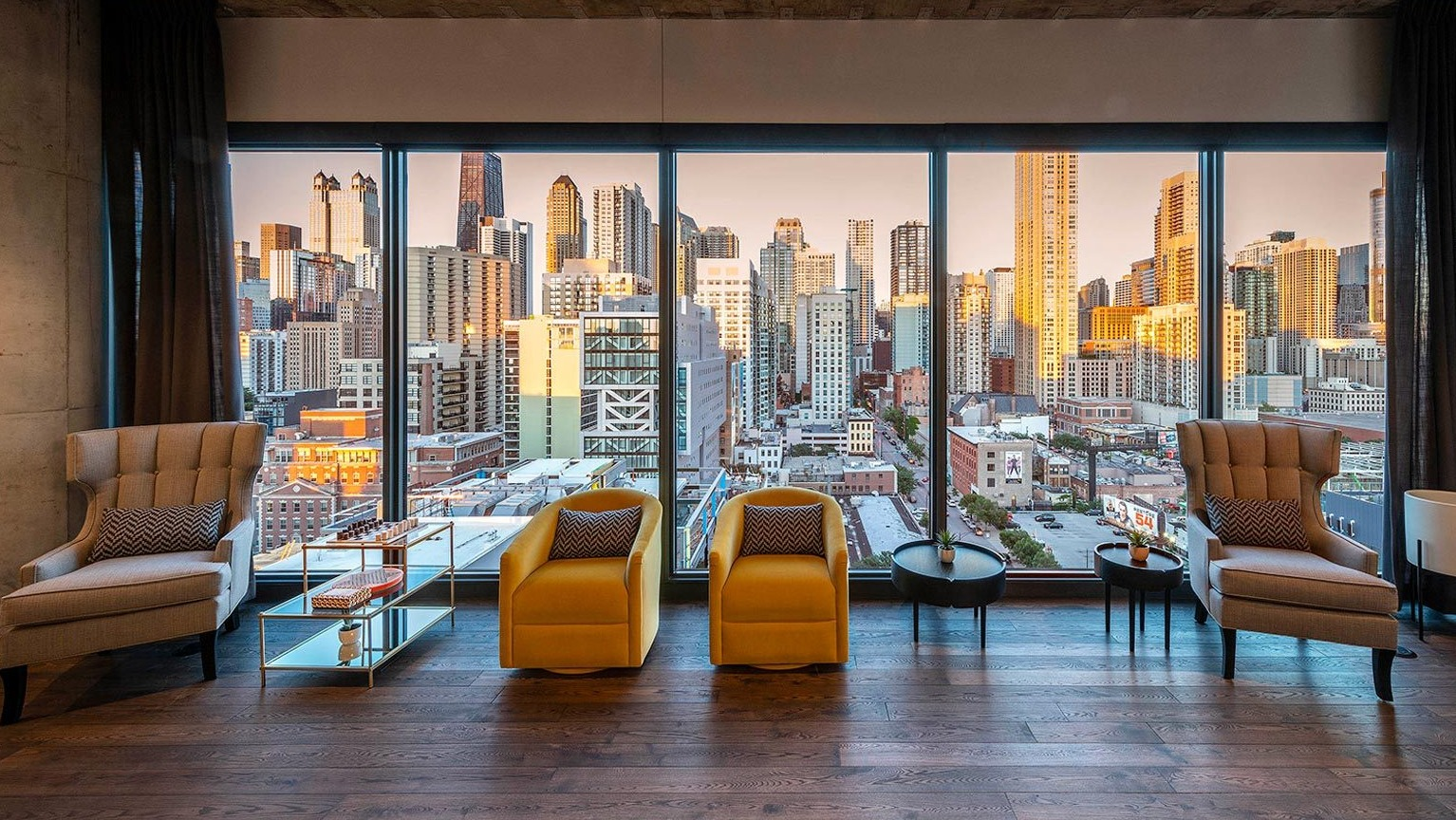 Elegant resident lounge featuring comfortable armchairs and floor-to-ceiling windows offering stunning panoramic city views at Marlowe Apartments in Chicago