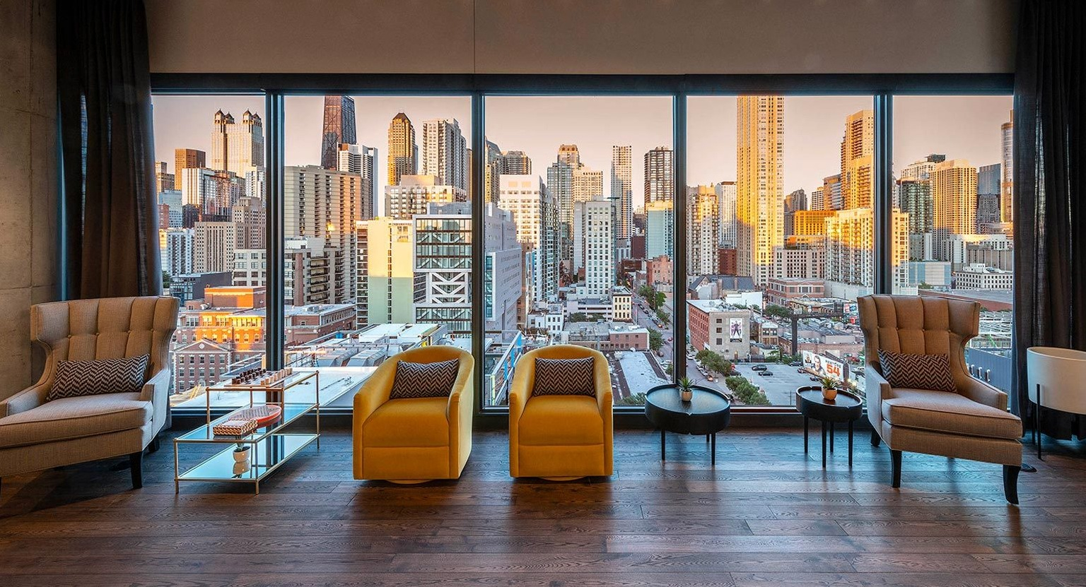 Elegant resident lounge featuring comfortable armchairs and floor-to-ceiling windows offering stunning panoramic city views at Marlowe Apartments in Chicago