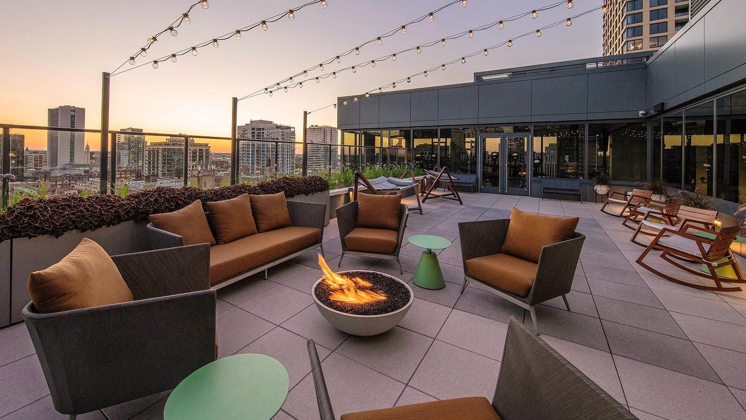 Inviting rooftop lounge area with a cozy fire pit, comfortable seating, and string lights, perfect for evening gatherings at Marlowe Apartments in Chicago