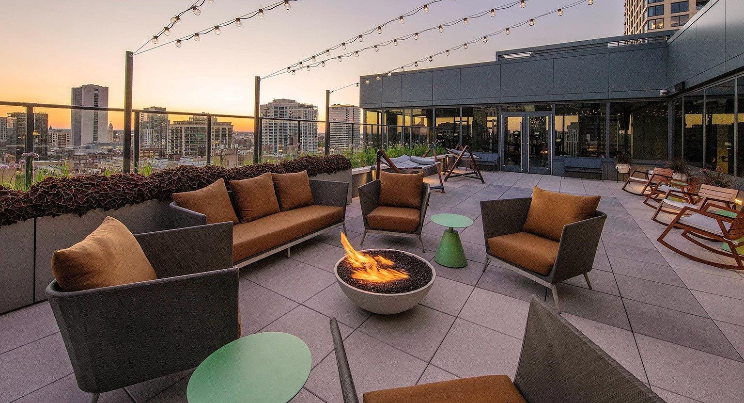 Inviting rooftop lounge area with a cozy fire pit, comfortable seating, and string lights, perfect for evening gatherings at Marlowe Apartments in Chicago