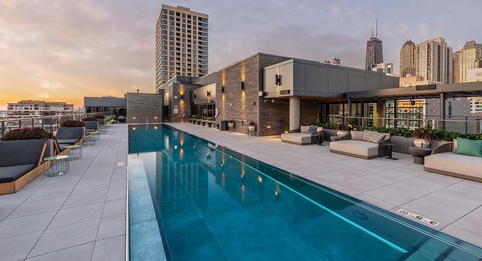 Luxurious rooftop swimming pool surrounded by lounge seating, offering breathtaking skyline views at Marlowe Apartments in Chicago