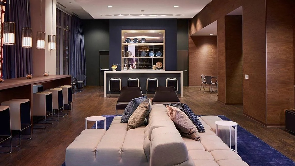 Elegant clubroom with a stylish bar, comfortable seating, and a large chandelier at Marquee at Block 37 apartments in Chicago