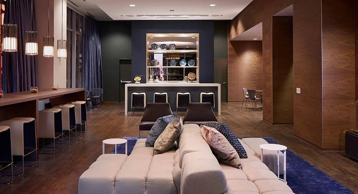 Elegant clubroom with a stylish bar, comfortable seating, and a large chandelier at Marquee at Block 37 apartments in Chicago