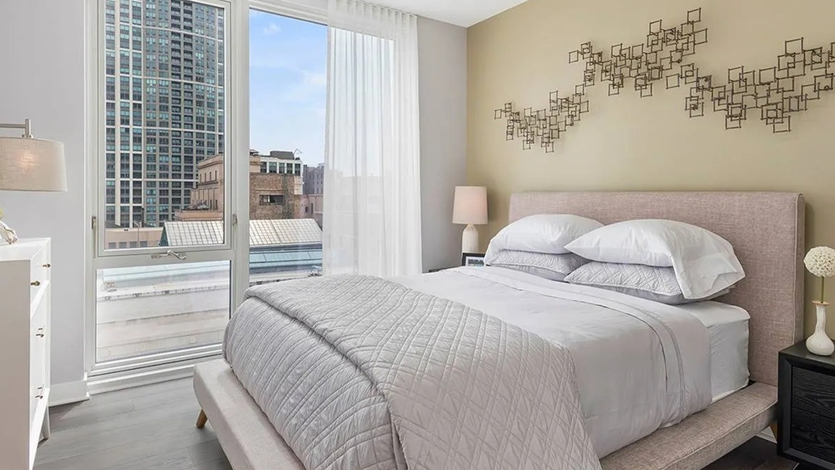 Bright and cozy bedroom with a comfortable bed, modern decor, and large windows offering city views at Marquee at Block 37 in Chicago