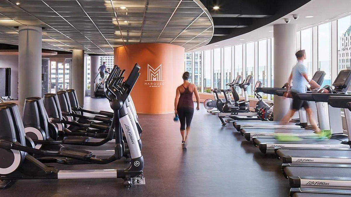 Spacious fitness center with a variety of cardio and weight training equipment, offering city views at Marquee at Block 37 in Chicago