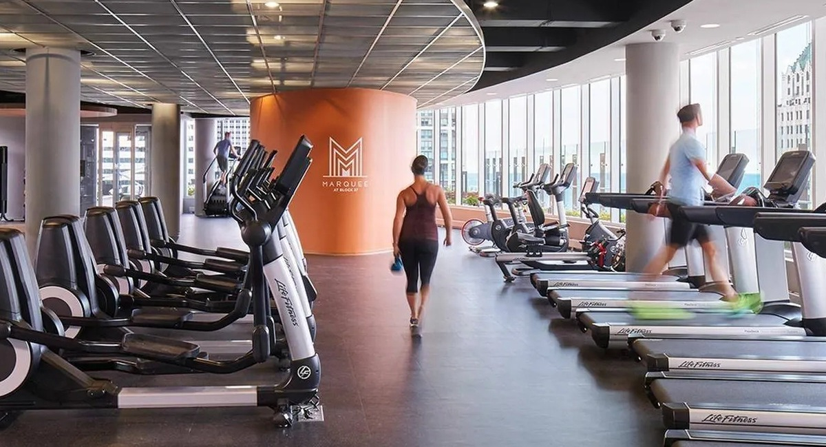Spacious fitness center with a variety of cardio and weight training equipment, offering city views at Marquee at Block 37 in Chicago