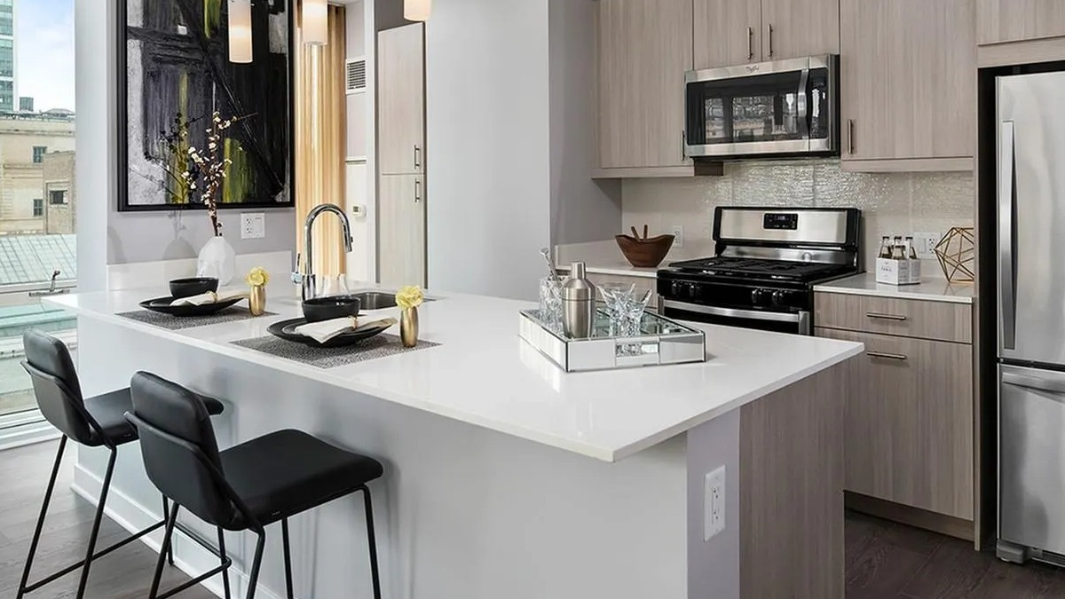 Sleek kitchen with a white island, pendant lighting, stainless steel appliances, and city views at Marquee at Block 37 in Chicago