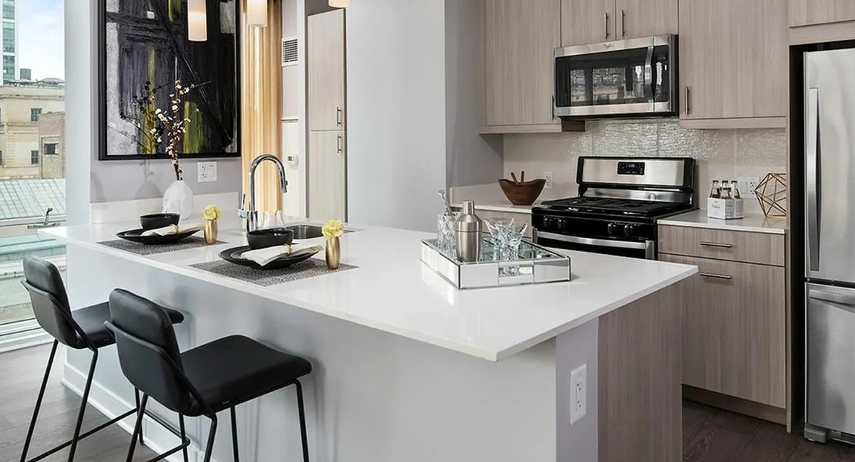 Sleek kitchen with a white island, pendant lighting, stainless steel appliances, and city views at Marquee at Block 37 in Chicago