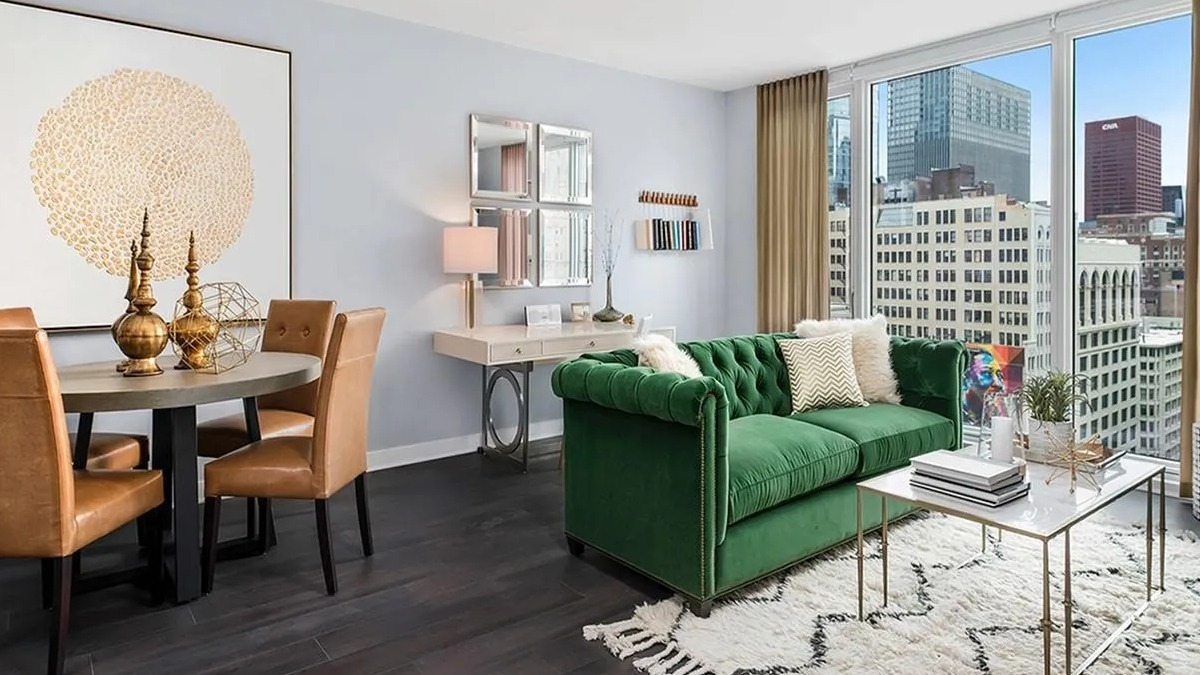 Modern living and dining area with a green sofa, stylish rug, and city views from large windows at Marquee at Block 37 in Chicago