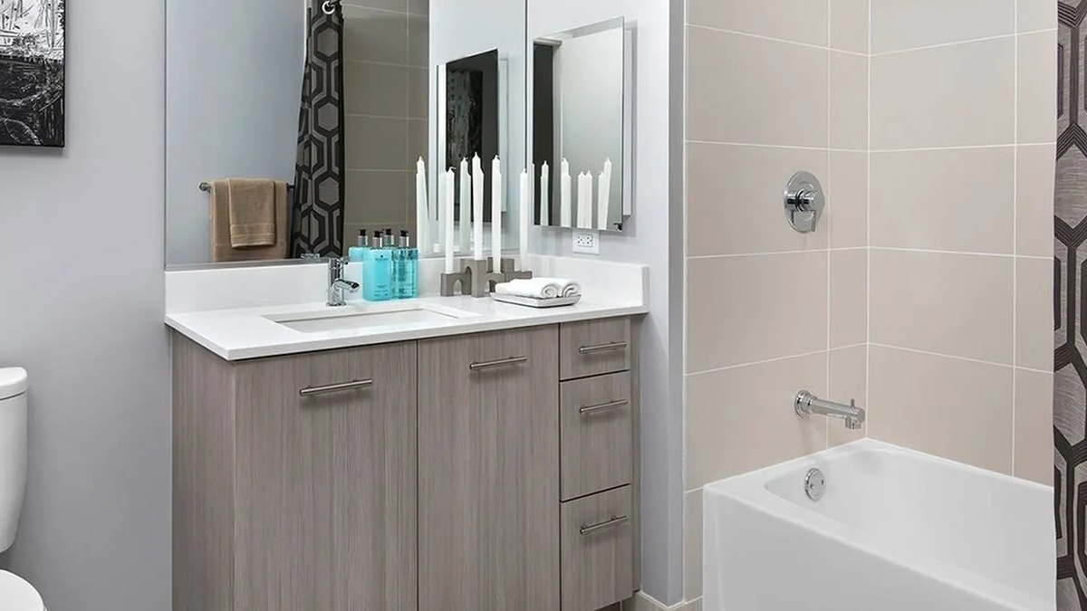 Contemporary bathroom with a large vanity, stylish mirror, and a clean bathtub and shower at Marquee at Block 37 apartments in Chicago