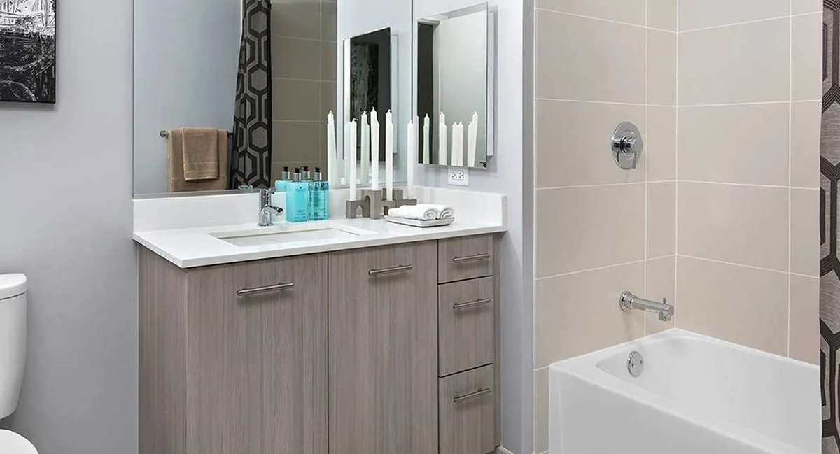 Contemporary bathroom with a large vanity, stylish mirror, and a clean bathtub and shower at Marquee at Block 37 apartments in Chicago