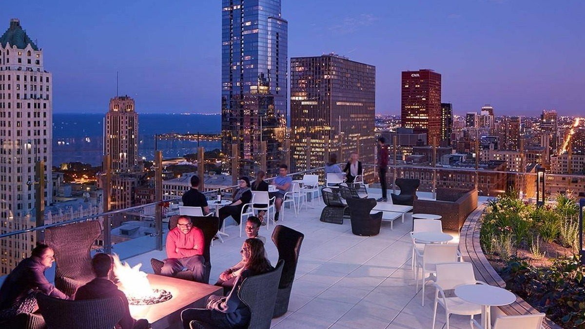 Residents gathered around a fire pit on a spacious rooftop terrace with panoramic night city and lake views at Marquee at Block 37 in Chicago