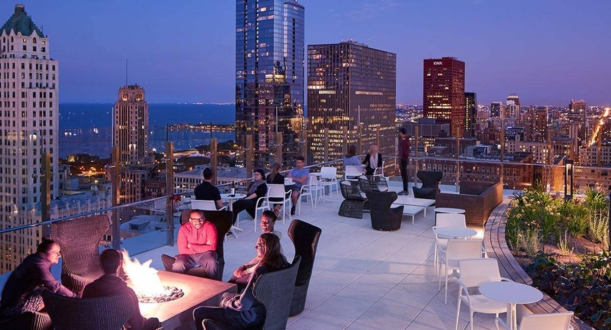 Residents gathered around a fire pit on a spacious rooftop terrace with panoramic night city and lake views at Marquee at Block 37 in Chicago
