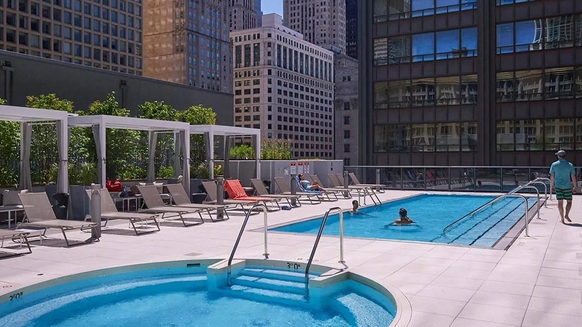Outdoor rooftop swimming pool and hot tub with lounge chairs and impressive city skyline views at Marquee at Block 37 in Chicago