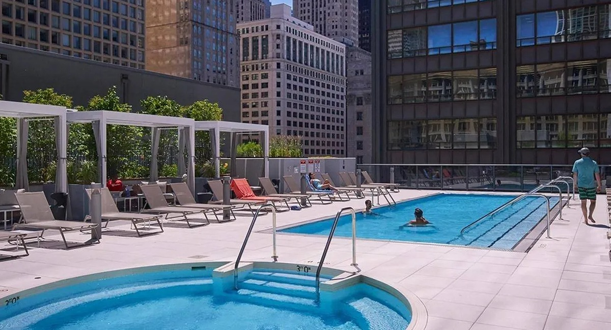 Outdoor rooftop swimming pool and hot tub with lounge chairs and impressive city skyline views at Marquee at Block 37 in Chicago
