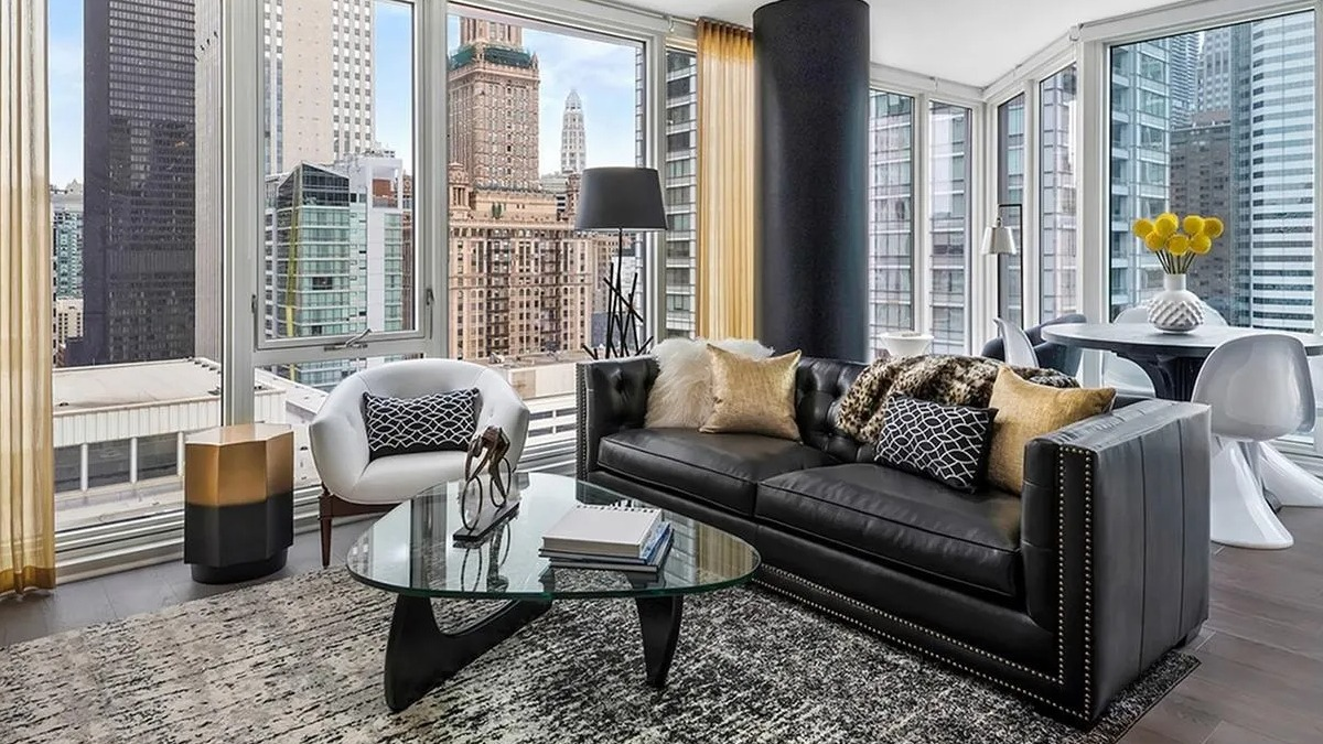 Expansive living room with a black leather sofa, large windows, and stunning panoramic city views at Marquee at Block 37 in Chicago