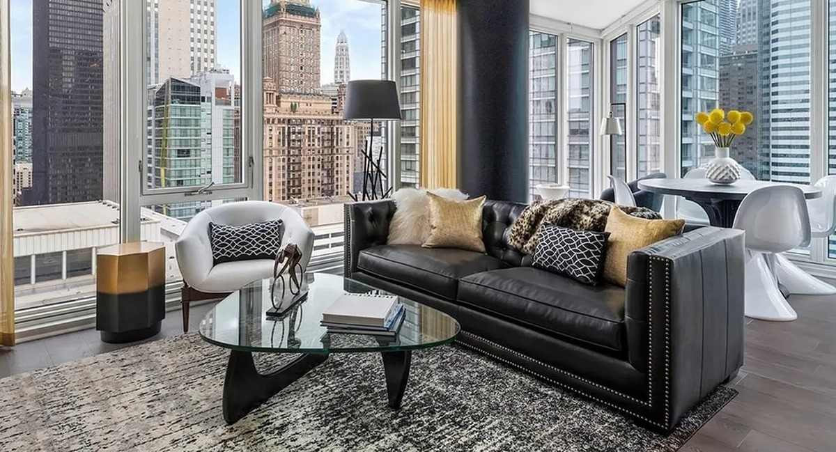 Expansive living room with a black leather sofa, large windows, and stunning panoramic city views at Marquee at Block 37 in Chicago
