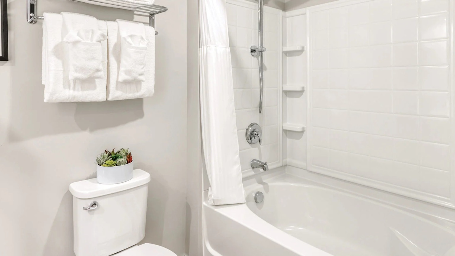 Clean and modern bathroom with a toilet, a shower-tub combination, and fresh towels at MDA Apartments in Chicago